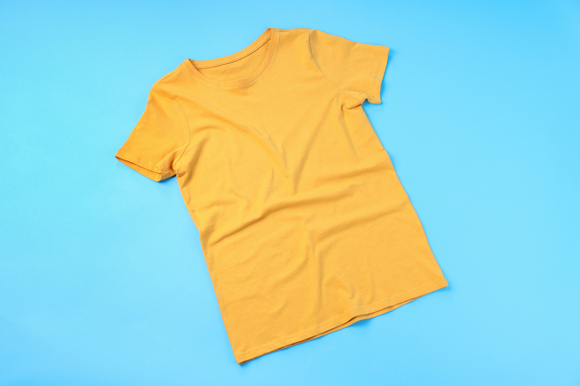 Blank yellow t-shirt with space for print on blue background